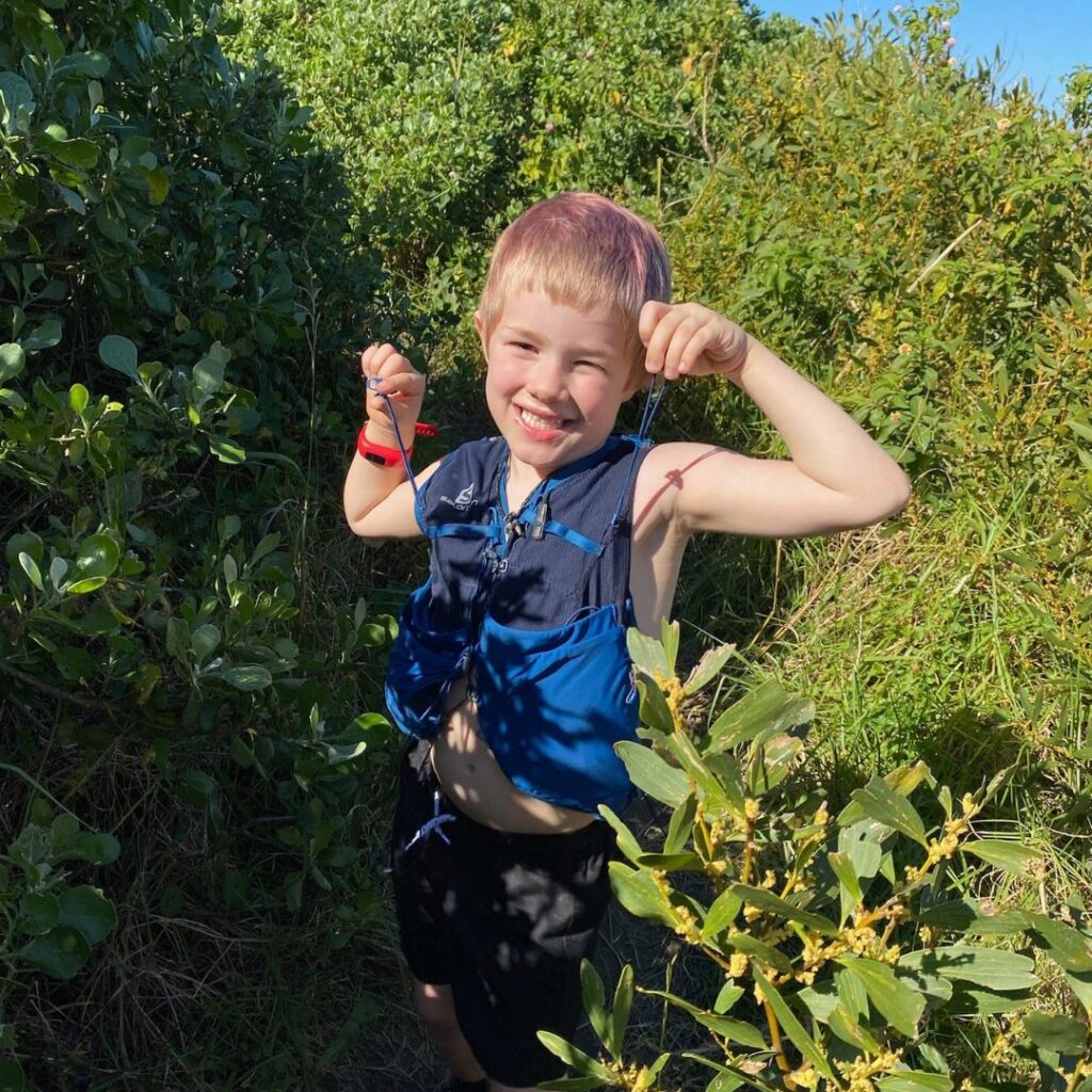 Child standing in the bush with running backpack on