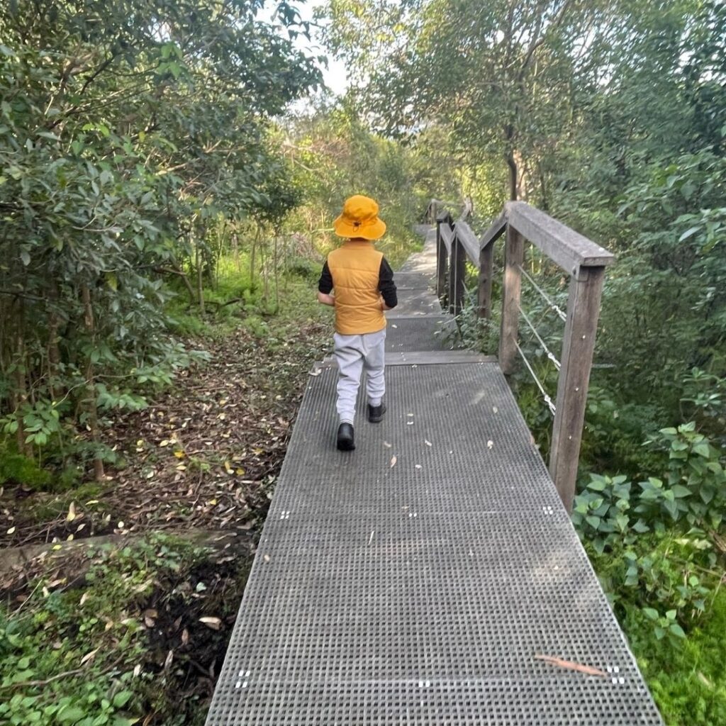 Child in yellow bucket hat on path in nature