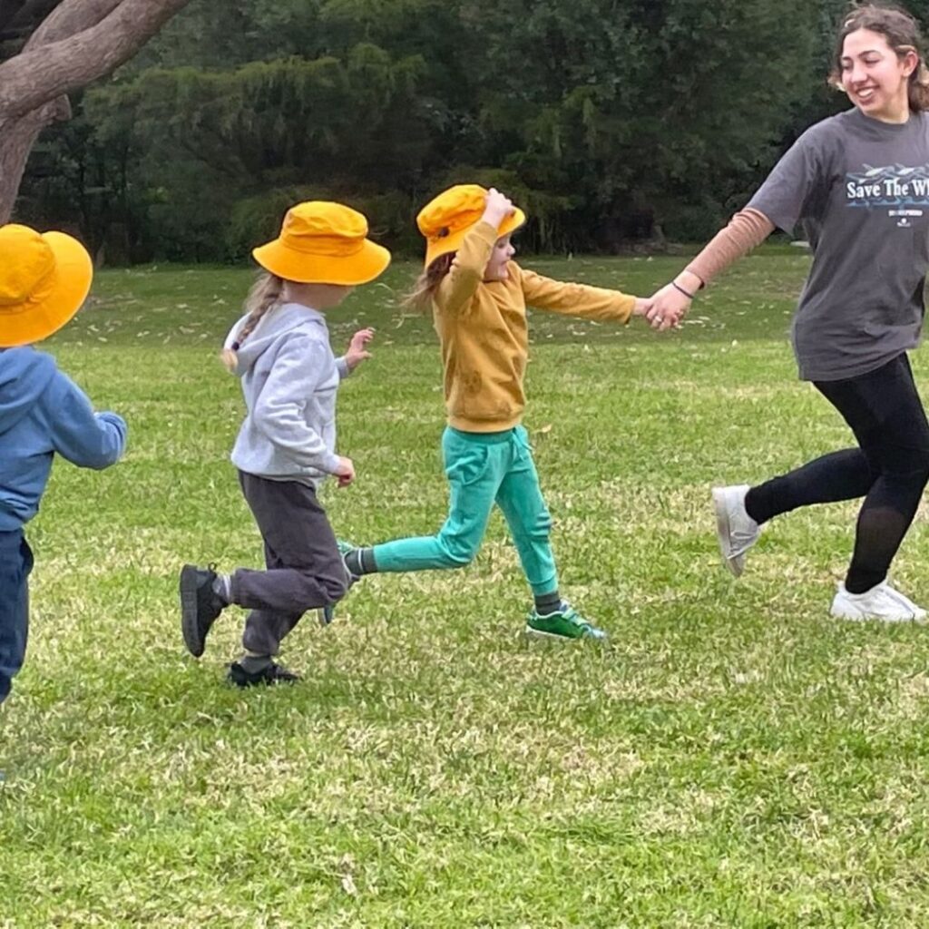 Happy children running on grass in yellow bucket hats
